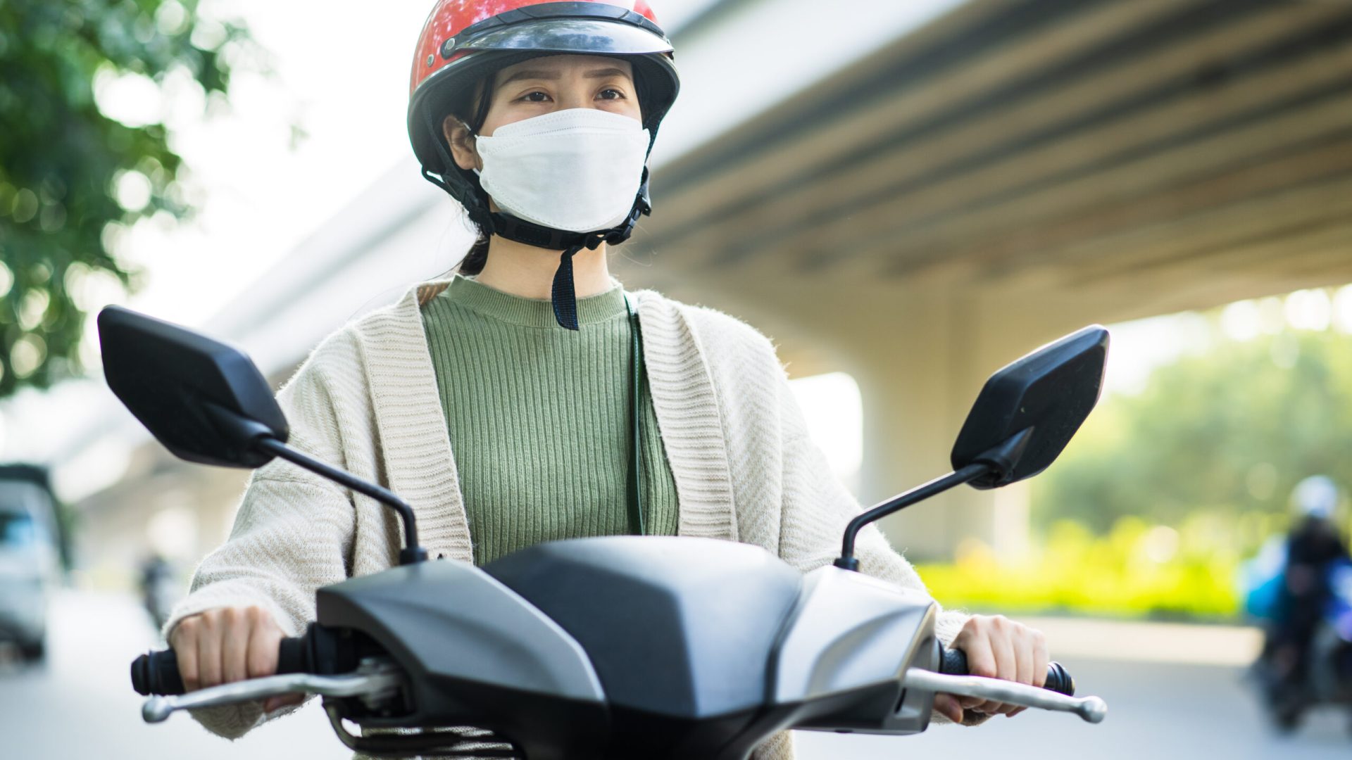 Asian woman driving a motorbike on her way to work