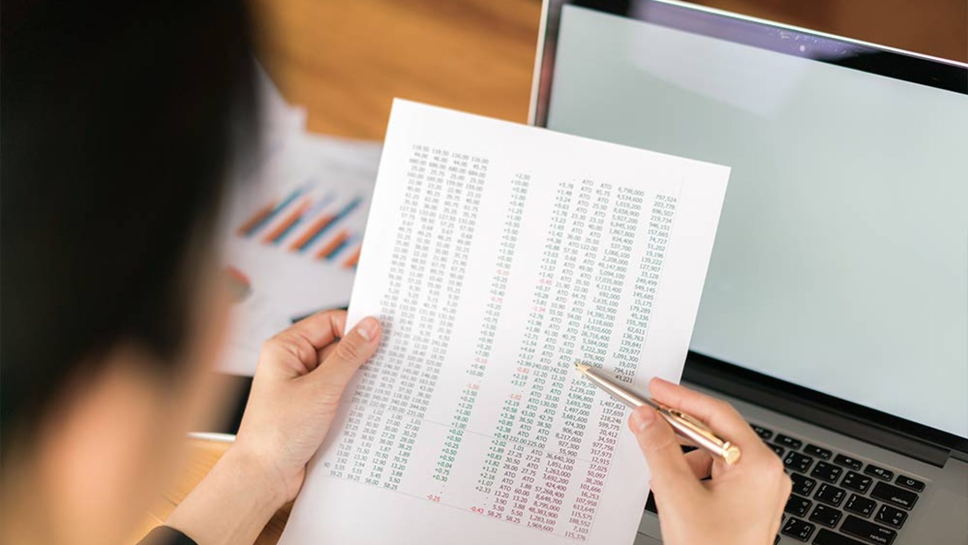 business-woman-hand-with-financial-charts-laptop-table