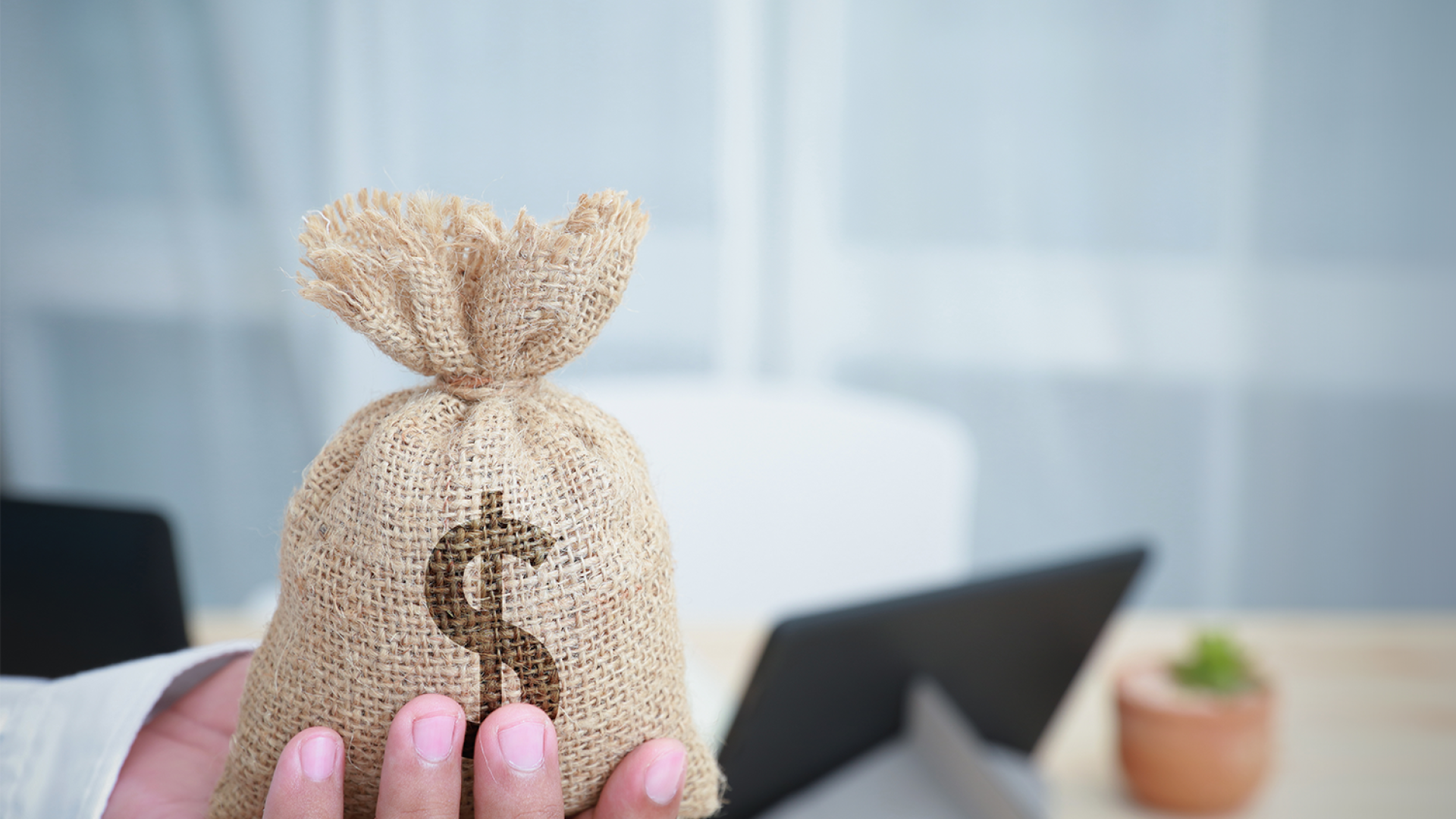 businessman-holding-out-dollar-money-bag-hand-with-copy-space-financial-support-tax-collection-investment-business-save-money-concepts