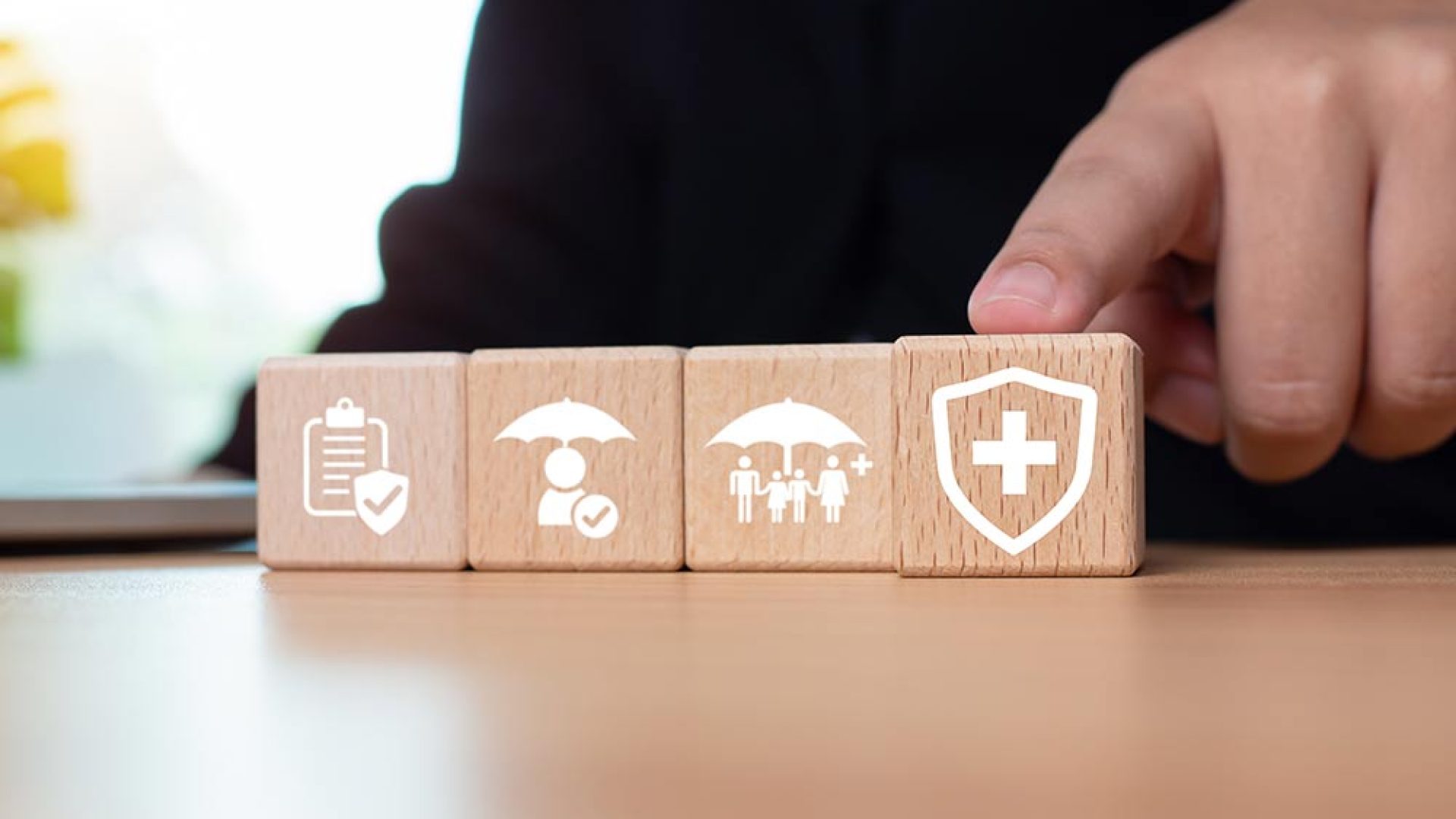 businessman-points-his-finger-wooden-block-printed-with-insurance-icons