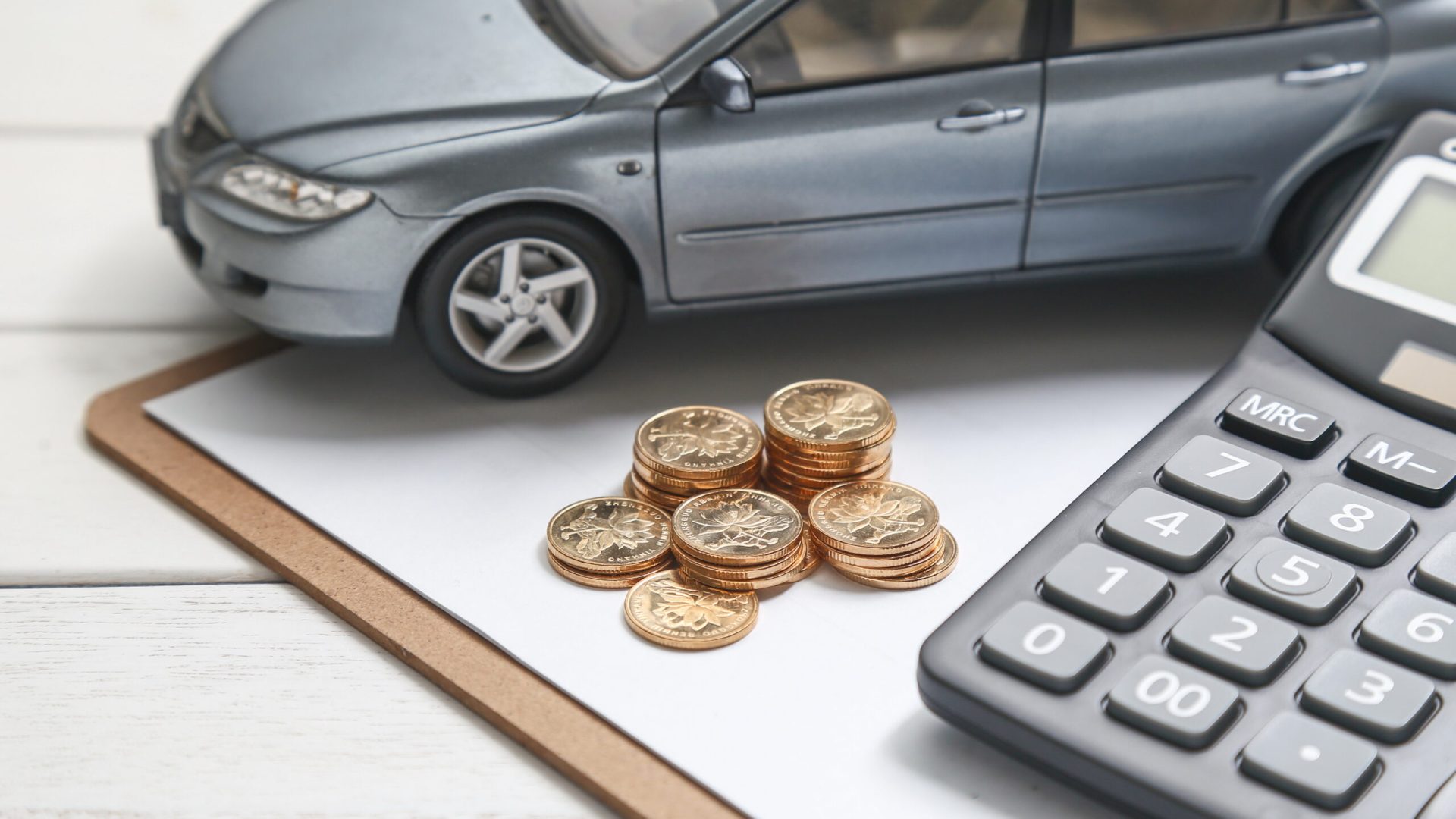 car model,calculator and coins on white table