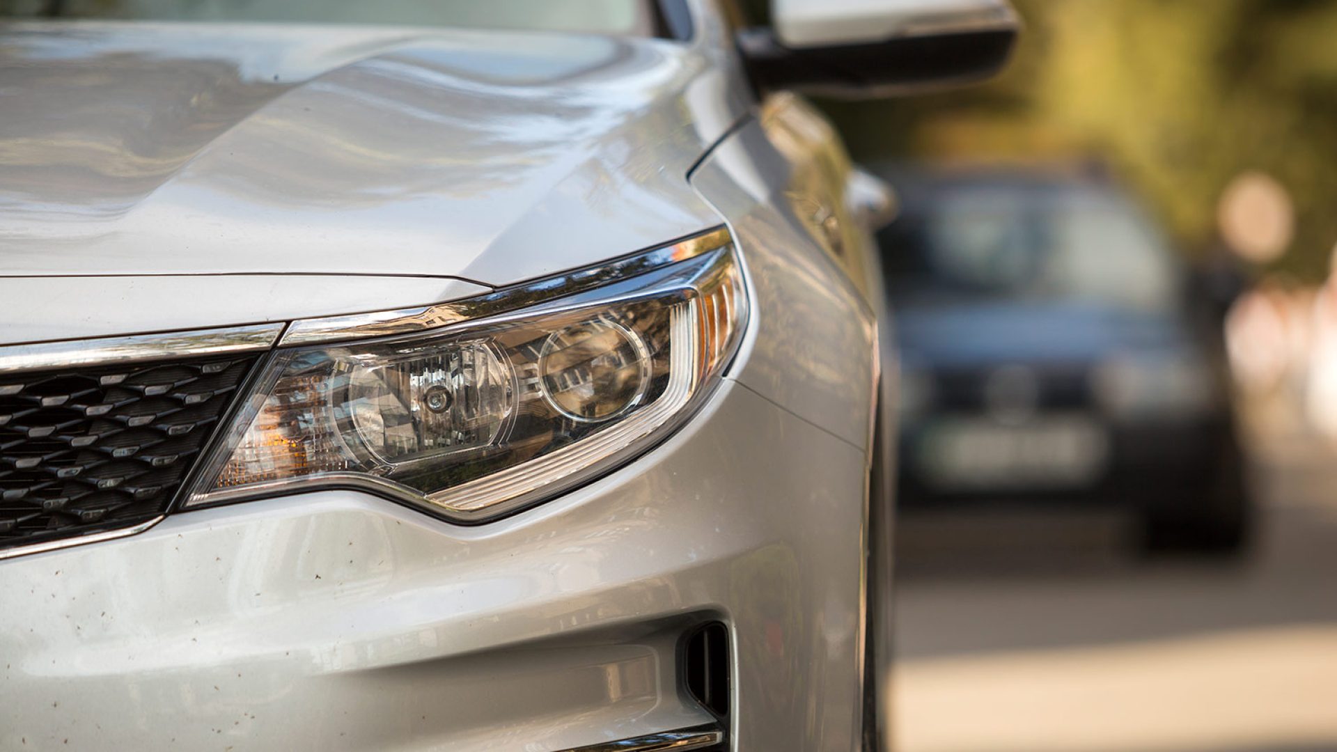 close-up-detail-part-silver-shiny-car-bumper-headlight-wheel-radiator-grille-blurred-outdoor