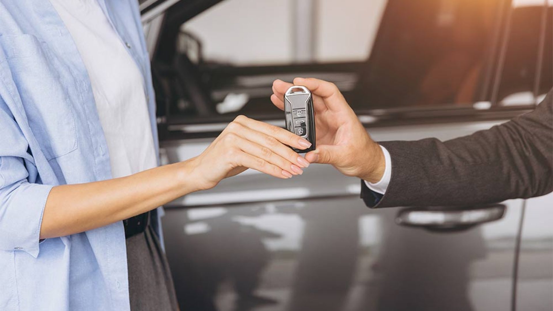 closeup-shot-salesman-manager-giving-car-keys-modern-woman-new-car-owner-car-dealership