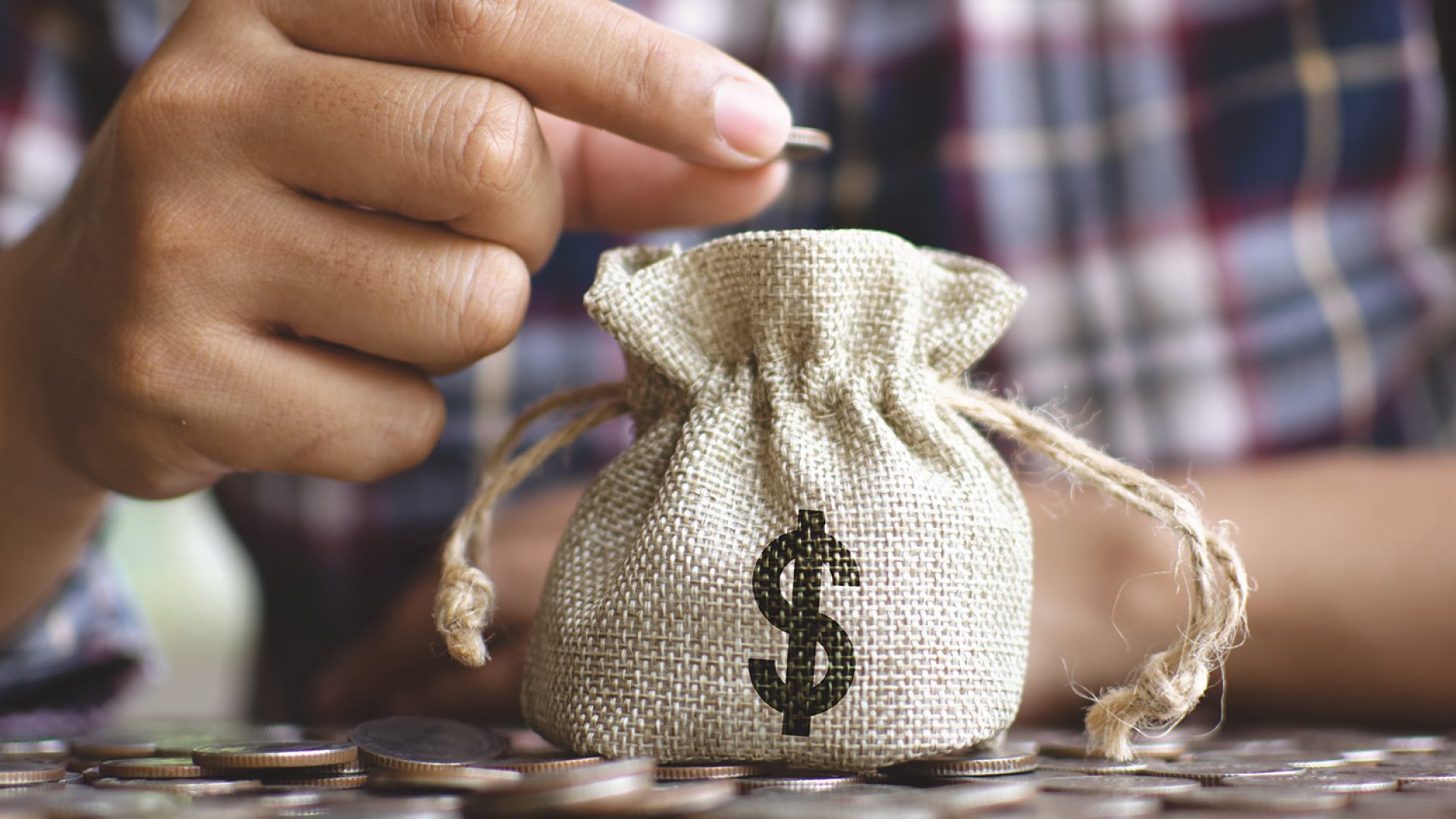 female-hands-dropping-money-bag-saving-money