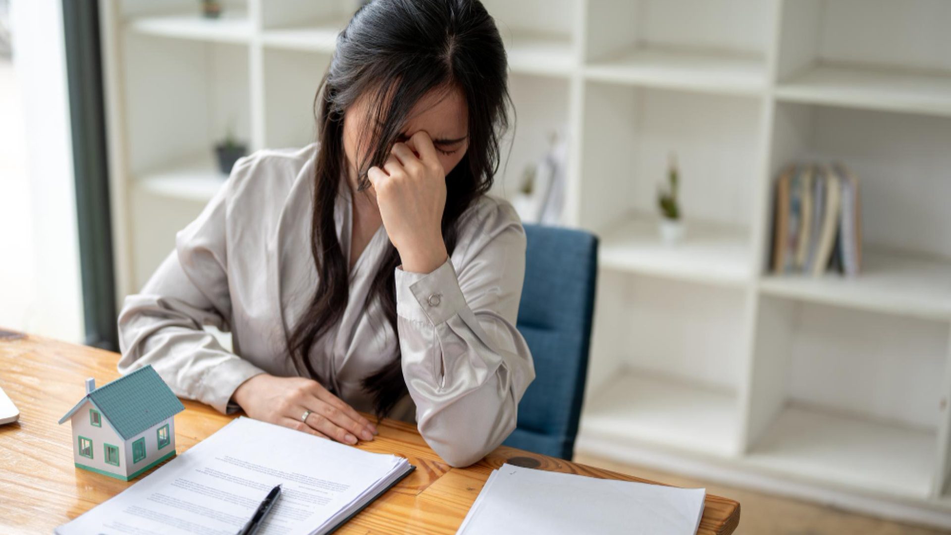stressed-upset-asian-female-real-estate-agent-is-sitting-her-desk-office