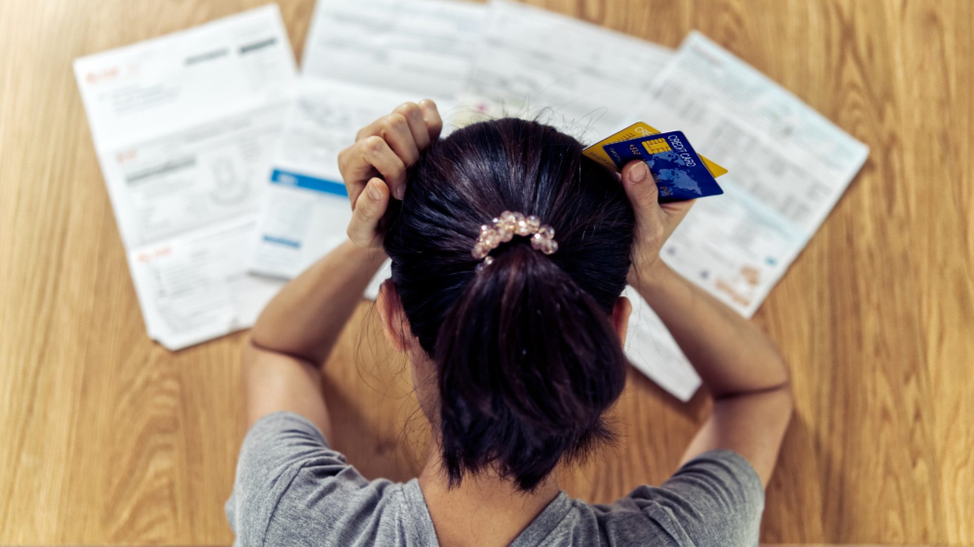 top-view-stressed-young-sitting-asian-woman-hands-holding-head-worry-about-find-money-pay-credit-card-debt-all-loan-bills