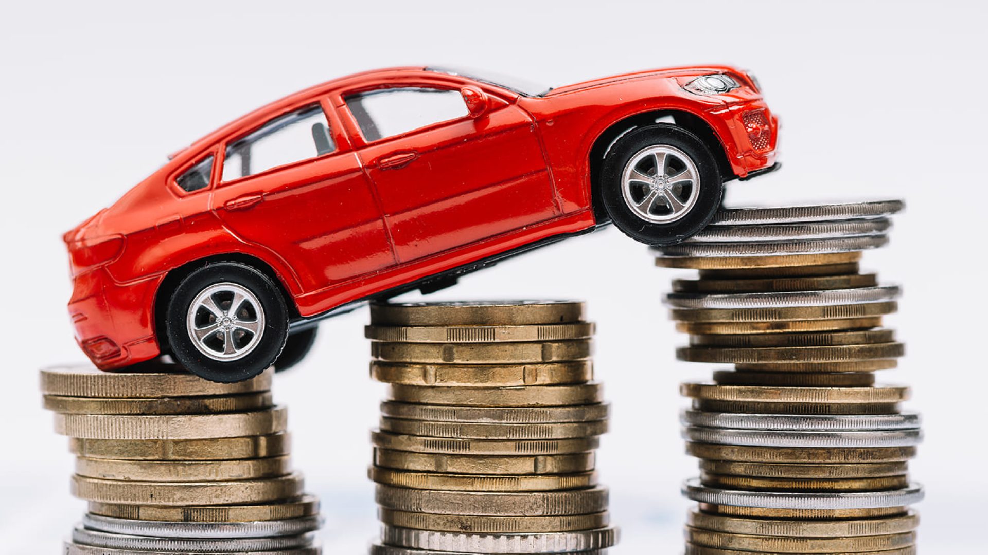 toy-red-car-stack-increasing-coins-against-white-background