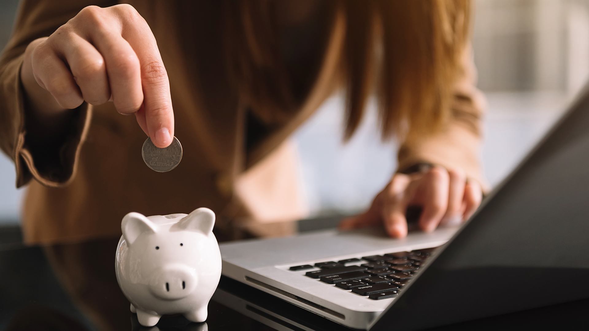 woman-hand-putting-coin-into-piggy-bank