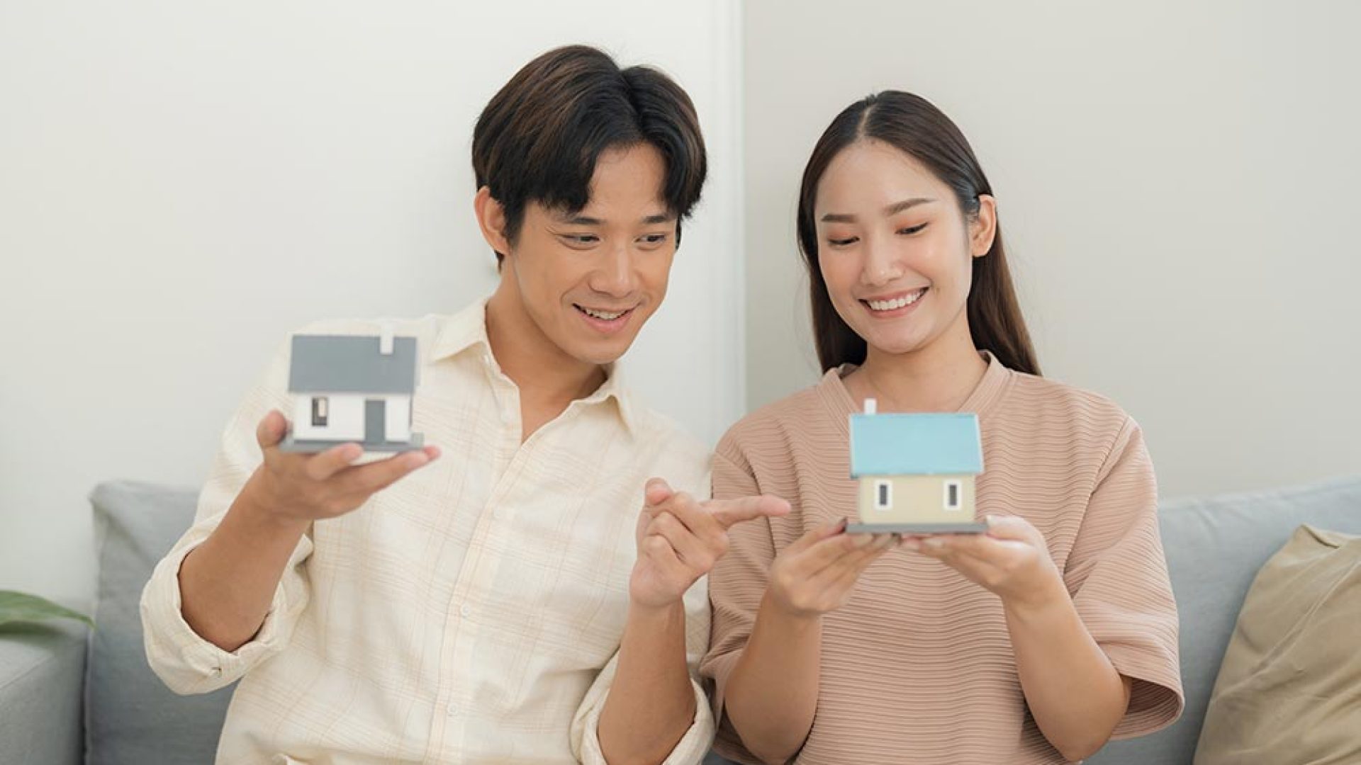 young-couple-holding-model-house-living-room